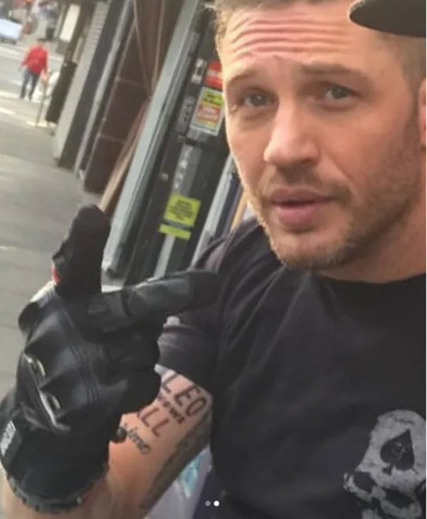 Ο Tom Hardy δείχνει ένα τατουάζ στο μπράτσο του.