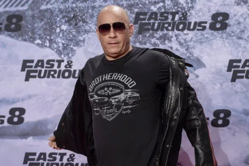 Ο Vin Diesel με γυαλιά ηλίου και μαύρο t-shirt μπροστά από αφίσα της ταινίας Fast & Furious 8.