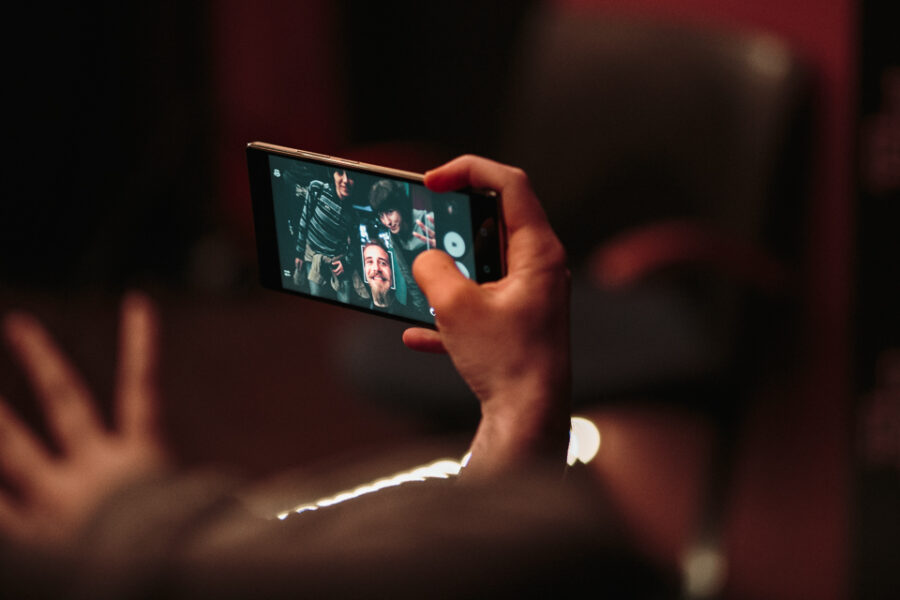 Ένα χέρι κρατάει smartphone και βγάζει φωτογραφία τρία άτομα σε πάρτι.
