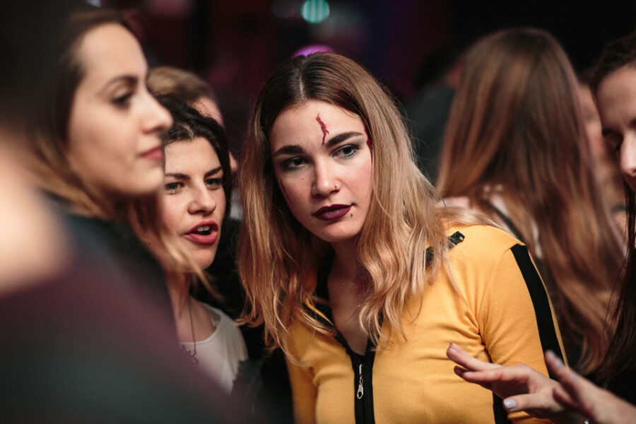 Κοπέλα με κίτρινη μπλούζα και μακιγιάζ με αίμα σε πάρτι Stranger Things.