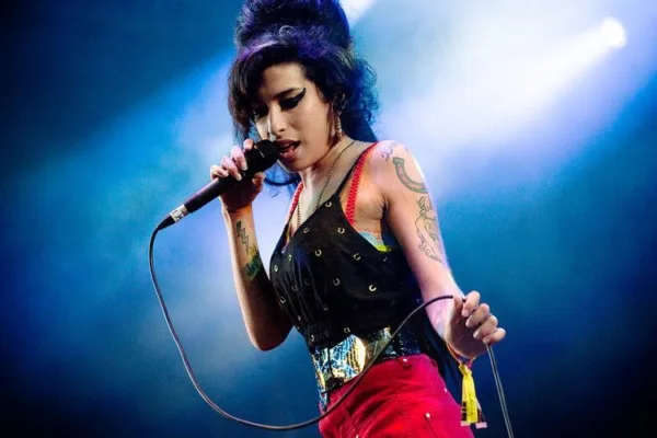 Η Amy Winehouse τραγουδάει σε σκηνή κρατώντας μικρόφωνο.