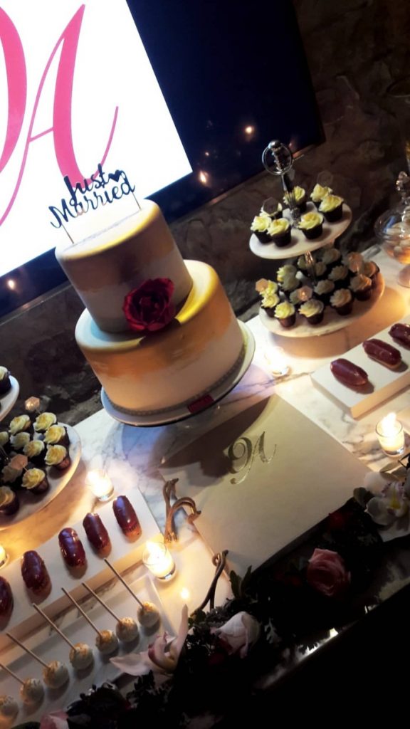 Τραπέζι γλυκών σε γάμο με διώροφη τούρτα και cupcakes.