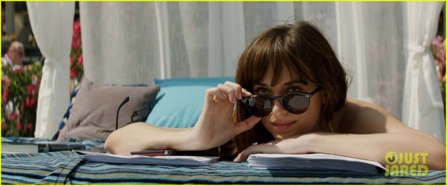 Η Dakota Johnson με γυαλιά ηλίου ξαπλωμένη σε εξωτερικό χώρο στην ταινία Fifty Shades Freed.