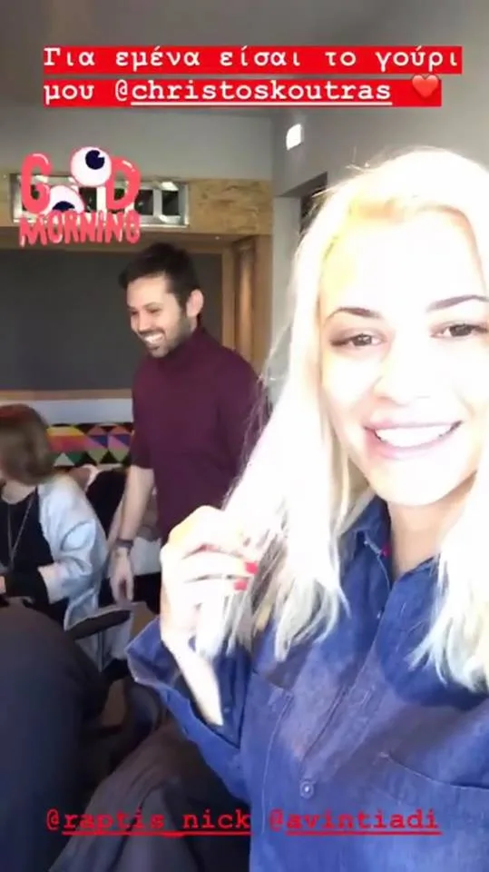 Η Λάουρα Νάργες σε selfie με φόντο έναν άνδρα και μια γυναίκα σε εσωτερικό χώρο.