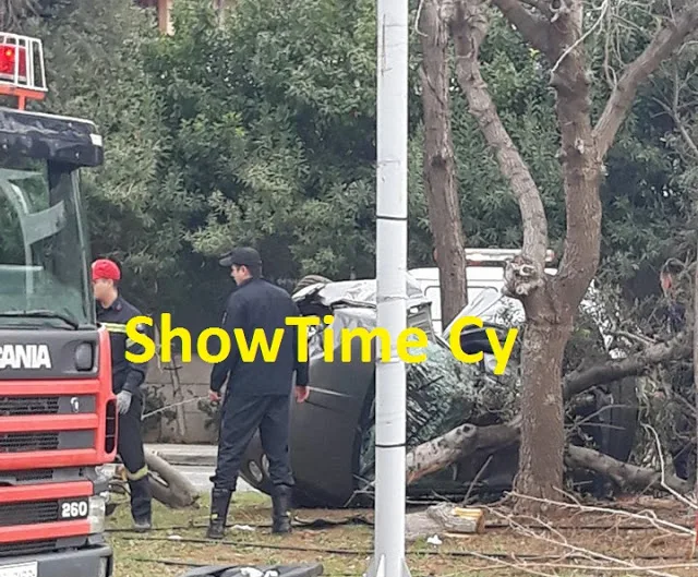 Σκηνή τροχαίου ατυχήματος με αναποδογυρισμένο αυτοκίνητο και πυροσβέστες.