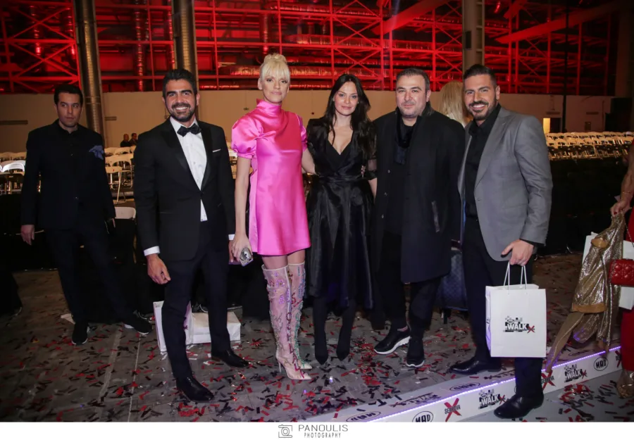 Πέντε άτομα ποζάρουν στο after party του MadWalk, ανάμεσά τους μια γυναίκα με ροζ φόρεμα και ψηλές μπότες.