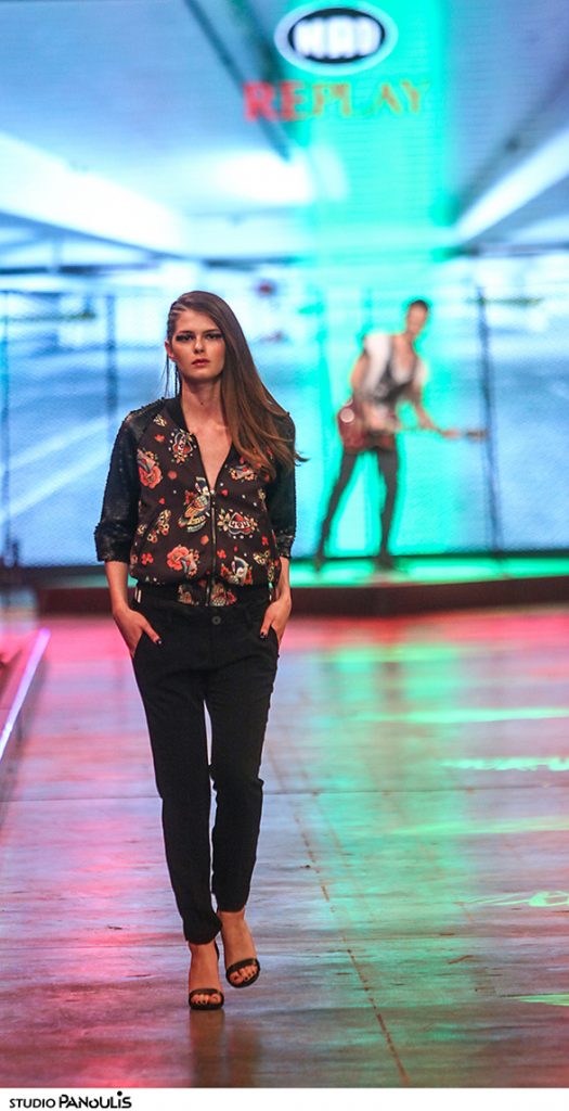 Μοντέλο στην πασαρέλα του MadWalk με εμπριμέ τζάκετ και μαύρο παντελόνι.