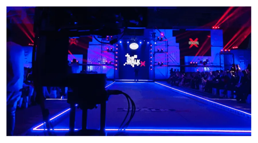 Άποψη της σκηνής του MadWalk 2018 by Serkova με μπλε φωτισμό και κάμερα σε πρώτο πλάνο.