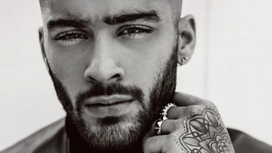 Κοντινό ασπρόμαυρο πορτρέτο του Zayn Malik με μούσι και τατουάζ στο χέρι.