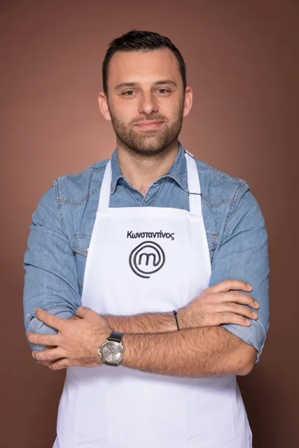 Παίκτης του MasterChef με λευκή ποδιά και σταυρωμένα χέρια.