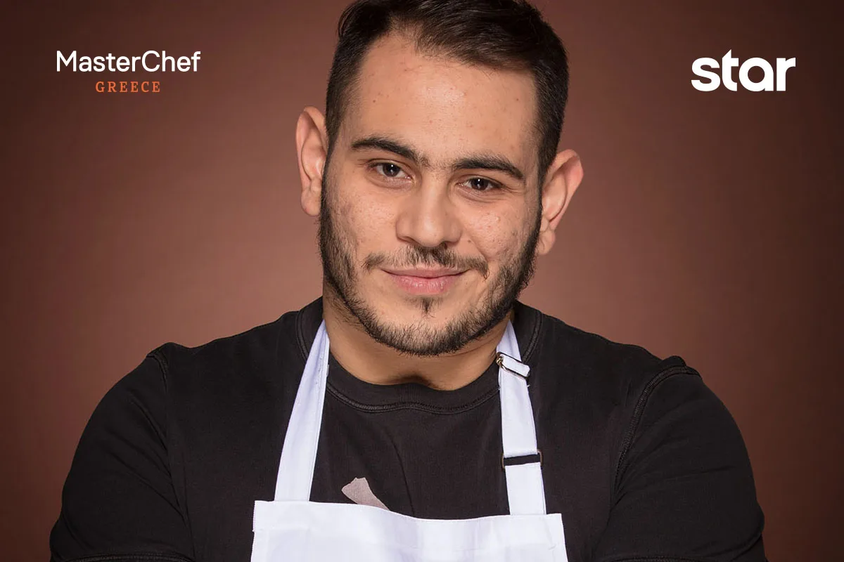 Παίκτης του MasterChef Greece με λευκή ποδιά και μαύρη μπλούζα.