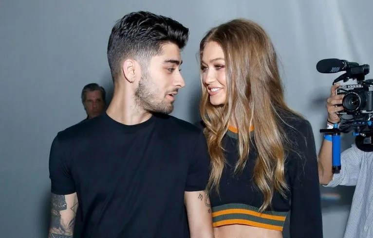 Ο Zayn Malik και η Gigi Hadid κοιτάζονται χαμογελαστοί σε εκδήλωση.