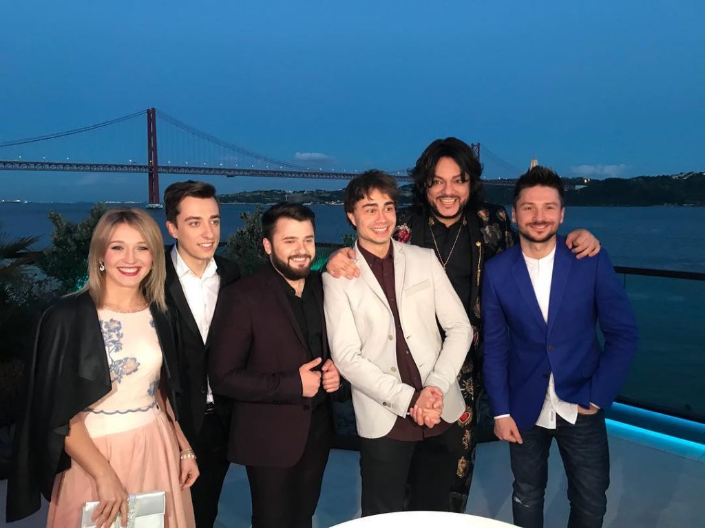 Ομάδα καλλιτεχνών της Eurovision 2018 ποζάρει με φόντο γέφυρα το σούρουπο.