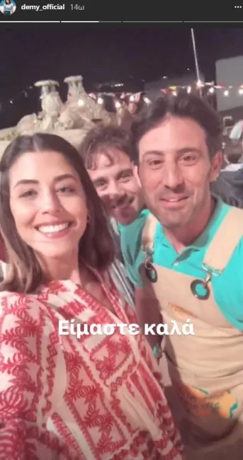 Η Demy χαμογελάει σε selfie με δύο άνδρες σε εξωτερικό χώρο.