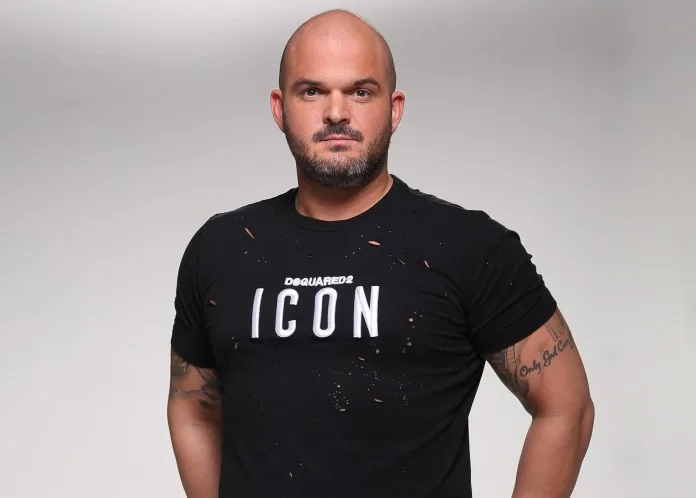 Άνδρας με μαύρο t-shirt Dsquared2 Icon και τατουάζ στο χέρι.