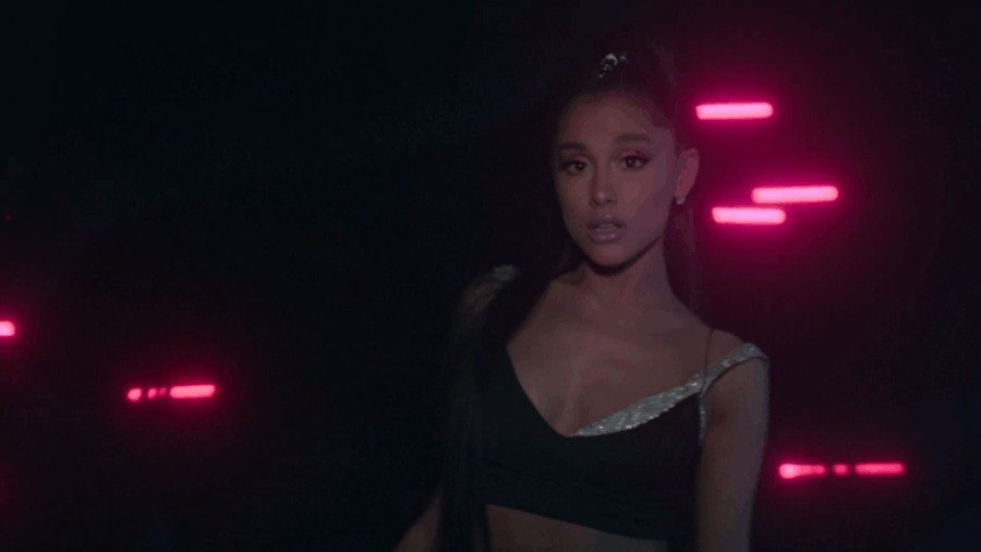Η Ariana Grande σε σκοτεινό σκηνικό με ροζ φώτα νέον.