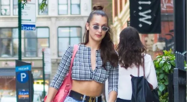 Η Bella Hadid περπατά στο δρόμο φορώντας καρό crop top και γυαλιά ηλίου.