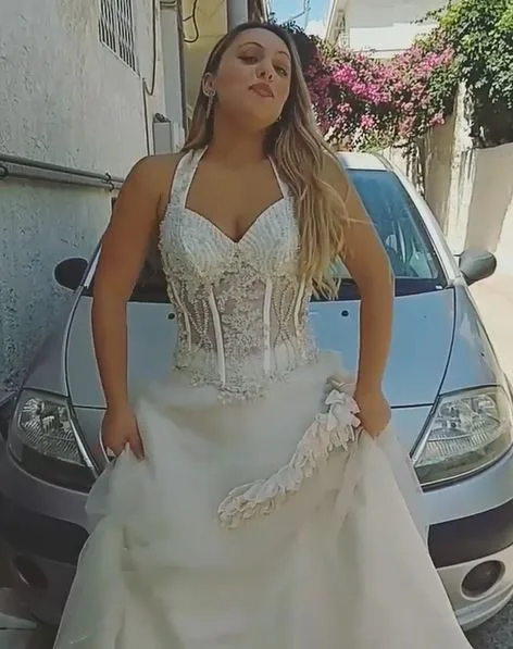 Η Κατερίνα από το Game Of Love με νυφικό μπροστά από ένα αυτοκίνητο.