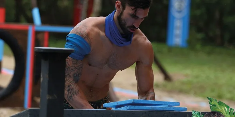 Άνδρας παίκτης του Survivor με μπλε μπαντάνα σε αγώνισμα.