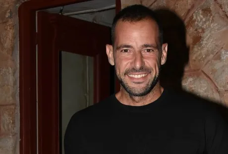 Ο Σώζων Παλαίστρος Χάρος χαμογελάει σε εσωτερικό χώρο.