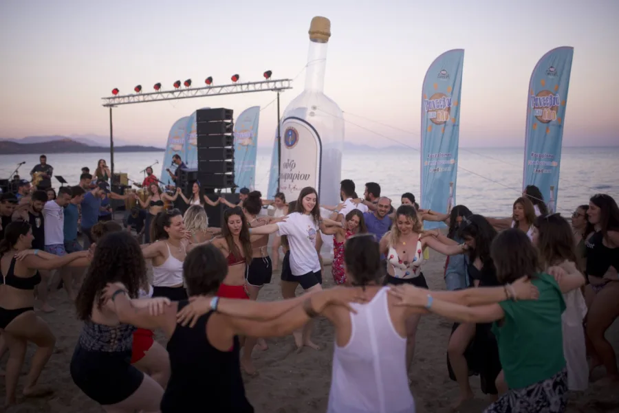 Κόσμος χορεύει σε κύκλο στην παραλία στο Mad Secret Ραντεβού στον Ήλιο.