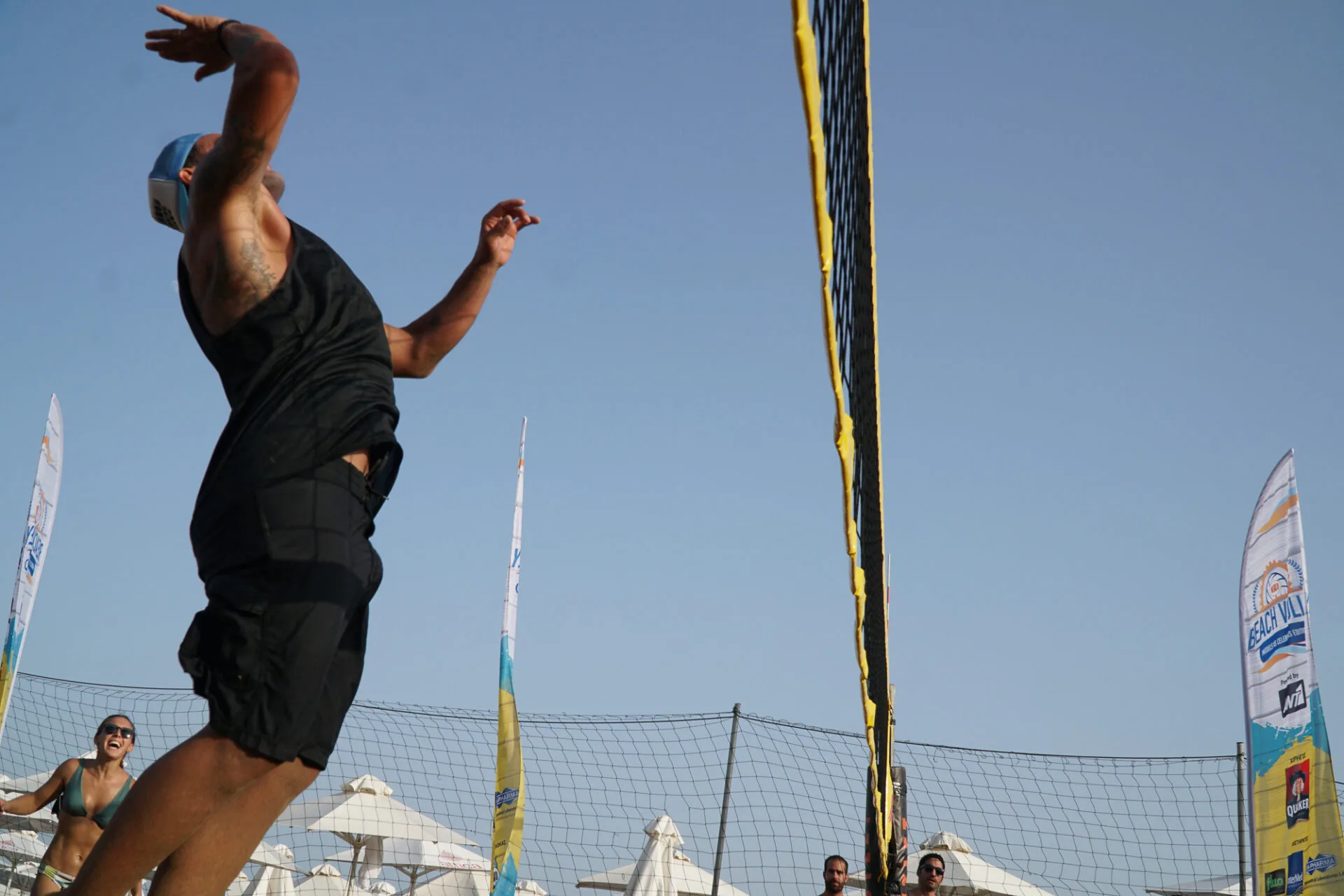 Άνδρας σε άλμα για καρφί σε αγώνα beach volley.