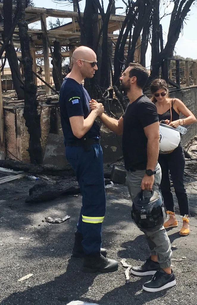Ο Σάκης Τανιμανίδης συνομιλεί με πυροσβέστη σε καμένη περιοχή.