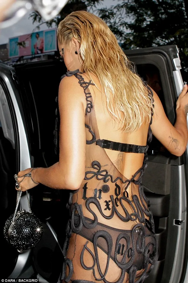 Η Rita Ora με αποκαλυπτικό μαύρο φόρεμα από δίχτυ και κεντημένα γράμματα.