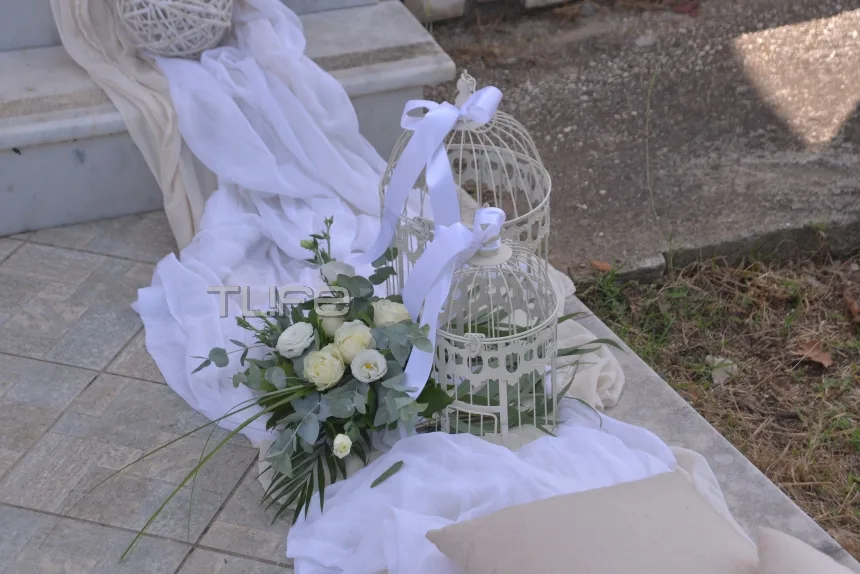 Στολισμός γάμου με λευκά υφάσματα, λουλούδια και διακοσμητικά κλουβιά.