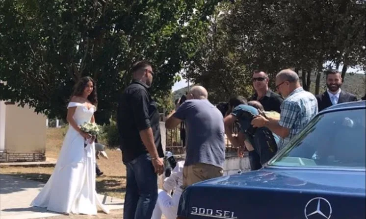 Η Κατερίνα Στικούδη νύφη με λευκό νυφικό και ανθοδέσμη περιτριγυρισμένη από κόσμο.