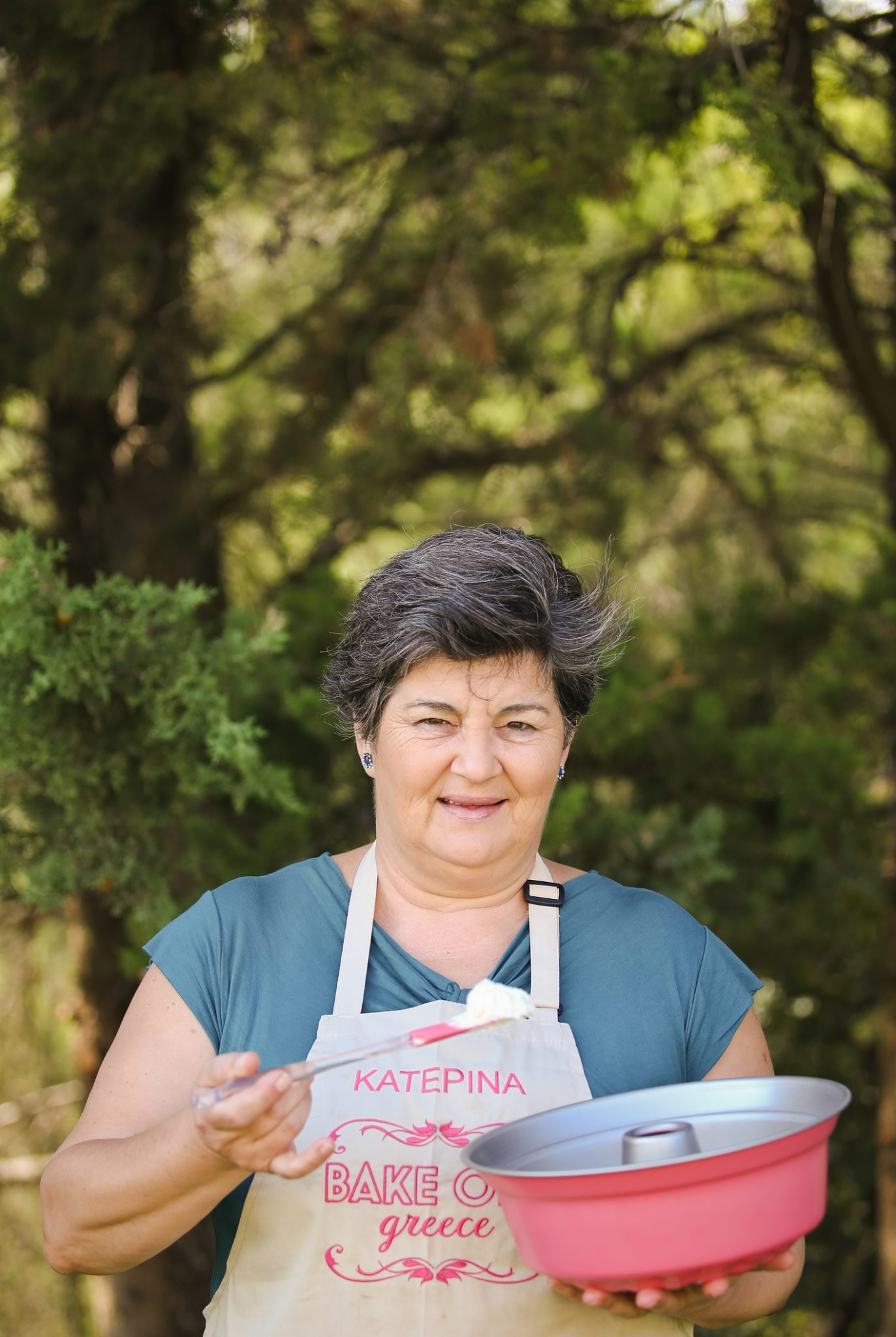 Η Κατερίνα, παίκτρια του Bake Off Greece, κρατάει μια φόρμα κέικ και μια σπάτουλα.