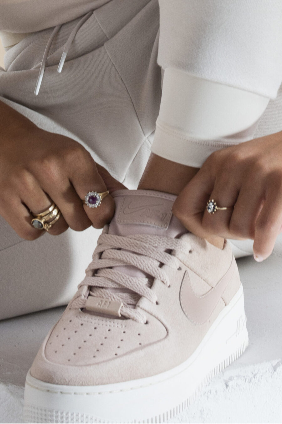 Κοντινό πλάνο σε Nike Air Force 1 Sage παπούτσια και χέρια με δαχτυλίδια.