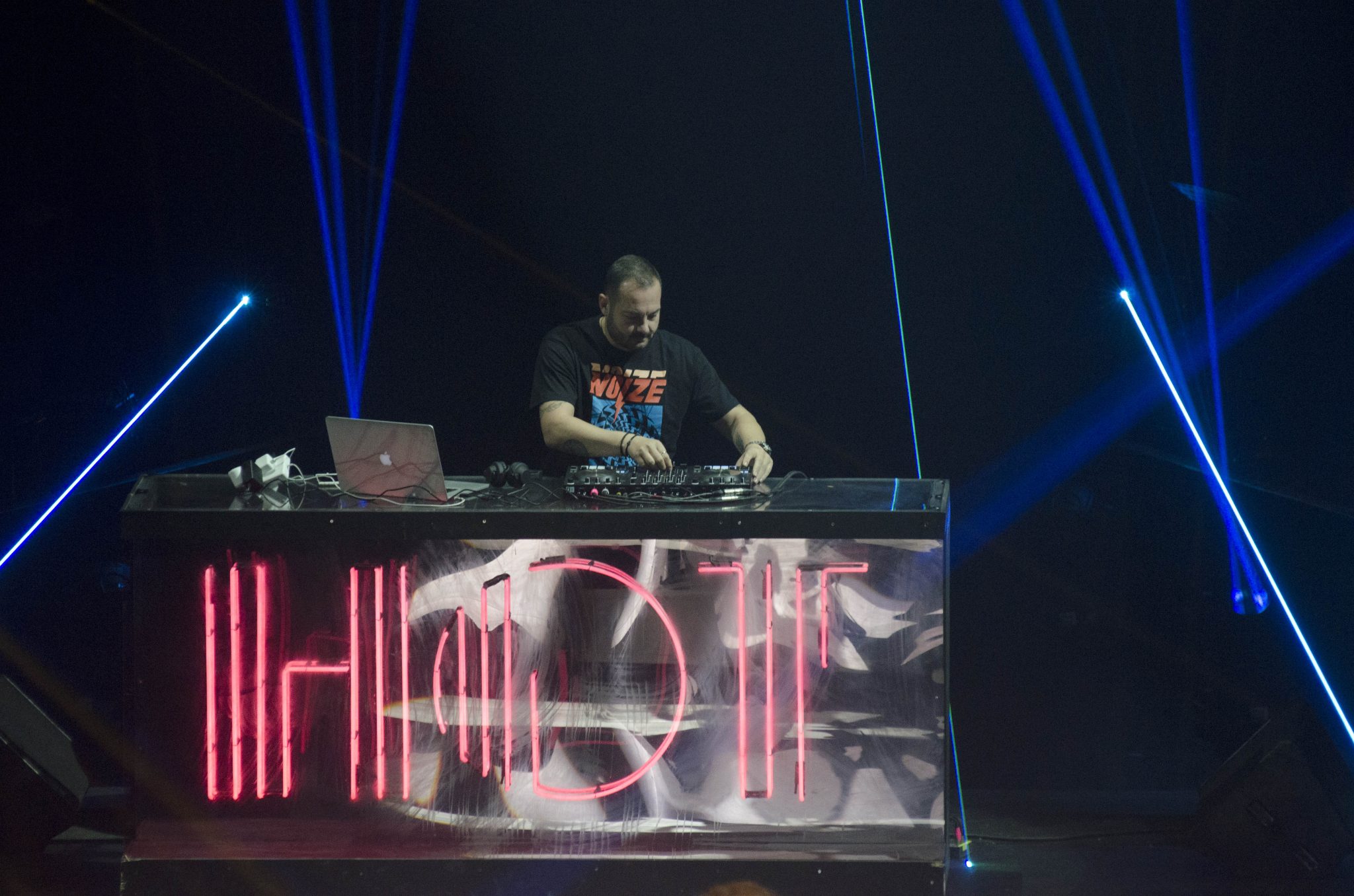 DJ σε σκηνή με λέιζερ και φωτεινό λογότυπο