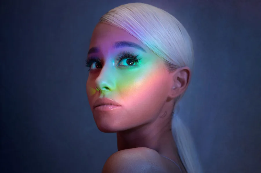 Η Ariana Grande με πλατινέ μαλλιά και πολύχρωμο φωτισμό ουράνιου τόξου στο πρόσωπο.