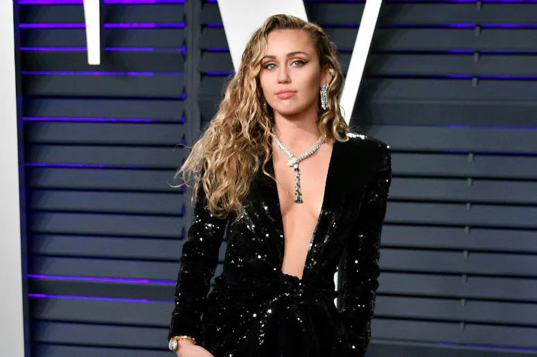 Η Miley Cyrus με μαύρο φόρεμα με παγιέτες και εντυπωσιακό κολιέ.