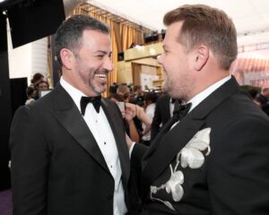 Δύο άνδρες με σμόκιν γελούν στο μωβ χαλί των Emmy Awards 2019.
