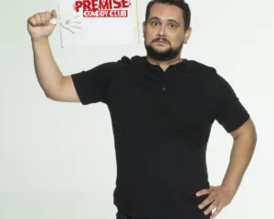 Ο κωμικός Πάρης Ρούπος κρατάει μια πινακίδα Premise Comedy Club.