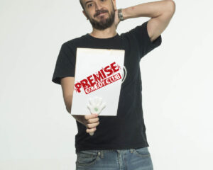 Ο κωμικός Πάρης Ρούπος κρατάει μια πινακίδα Premise Comedy Club.