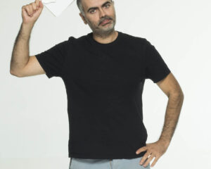 Ο Πάρης Ρούπος κρατάει μια πινακίδα Premise Comedy Club.