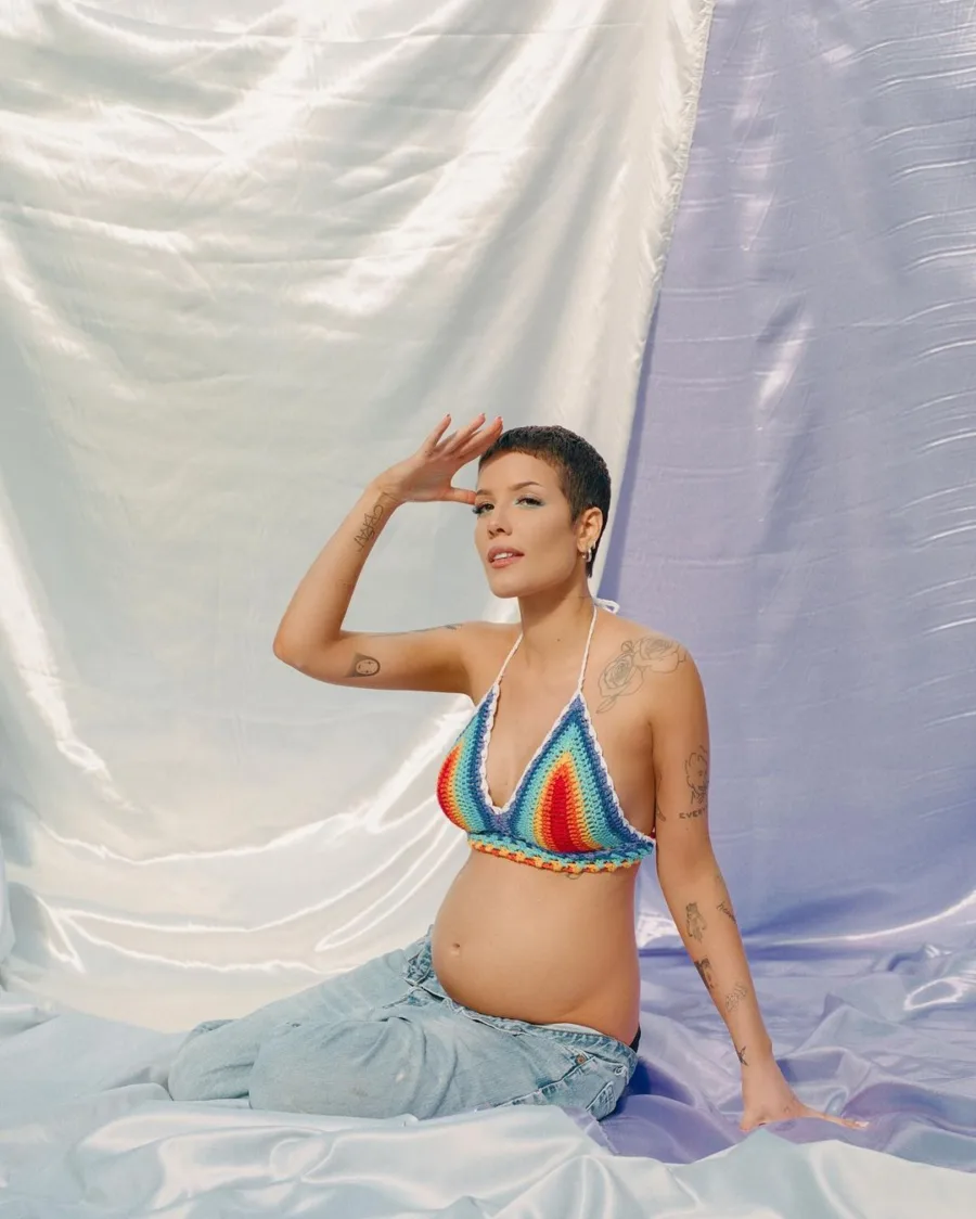 Η Halsey ποζάρει έγκυος με πλεκτό πολύχρωμο τοπ και τζιν παντελόνι.