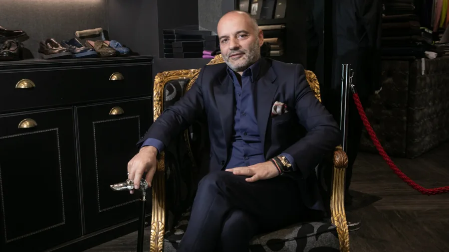 Ο G. Papadogamvros κάθεται σε πολυθρόνα κρατώντας μπαστούνι.