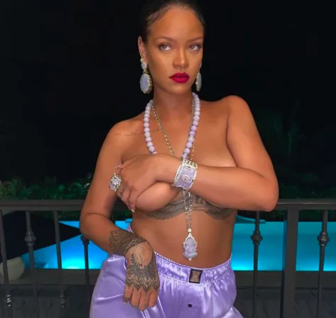 Η Rihanna ποζάρει γυμνόστηθη με μωβ κοσμήματα και παντελόνι.