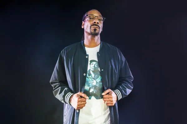 Ο Snoop Dogg με γυαλιά και μπλε τζάκετ πάνω από λευκό t-shirt.