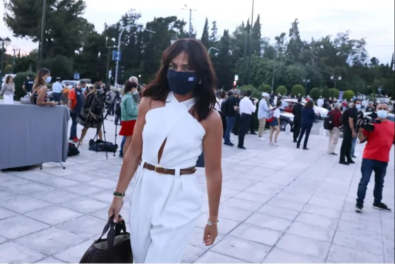Γυναίκα με λευκή ολόσωμη φόρμα και μάσκα προστασίας στο show Dior Celebrates Greece.