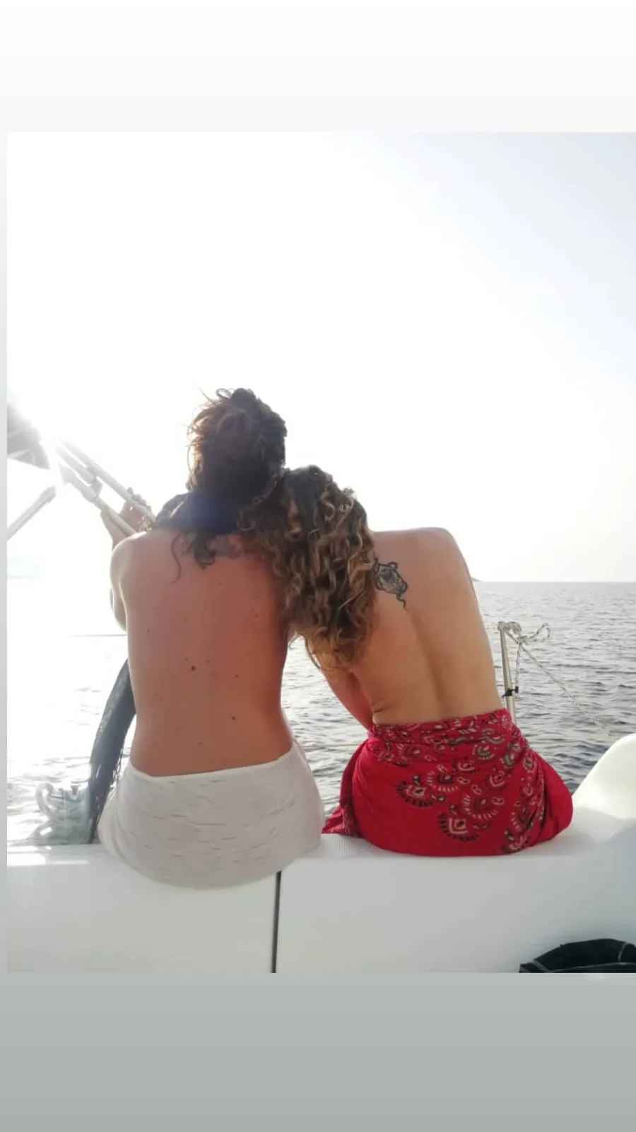 Η Έλλη Τρίγγου και μία φίλη της ποζάρουν topless στην πρύμνη ενός σκάφους στη θάλασσα.