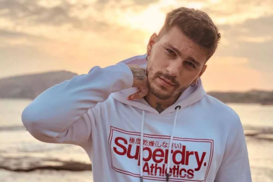 Ο Steve Milatos με λευκό φούτερ Superdry σε εξωτερικό χώρο.