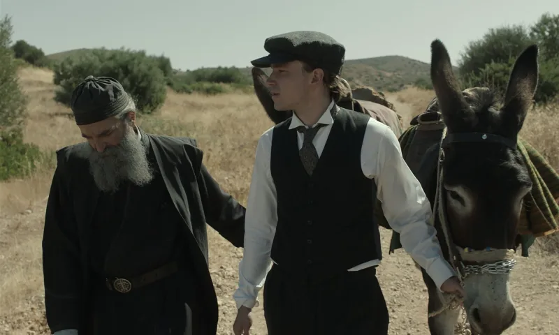 Σκηνή από την ταινία Ο Άνθρωπος του Θεού με έναν ιερέα και έναν νεαρό άνδρα δίπλα σε ένα γαϊδούρι.