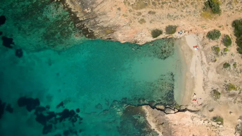 Αεροφωτογραφία μιας μικρής, απομονωμένης παραλίας με γαλαζοπράσινα νερά στην Αττική.