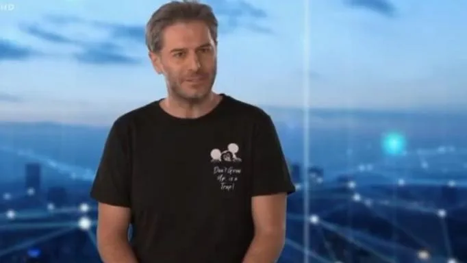 Ο Αλέξανδρος Μπουρδούμης με μαύρο t-shirt σε φόντο πόλης.