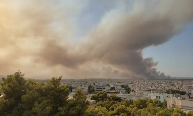 Πυκνοί καπνοί από μεγάλη πυρκαγιά πάνω από αστική περιοχή.